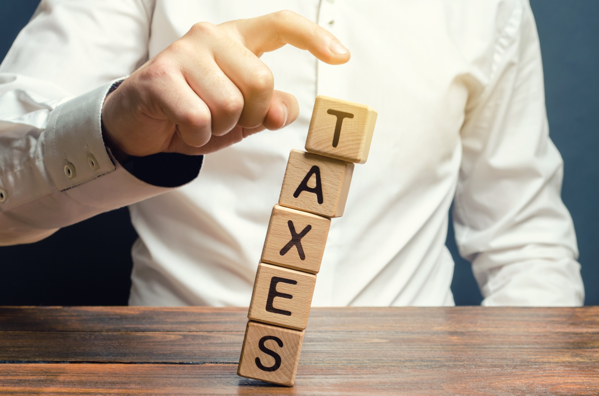Businessman removes wooden blocks with the word Taxes