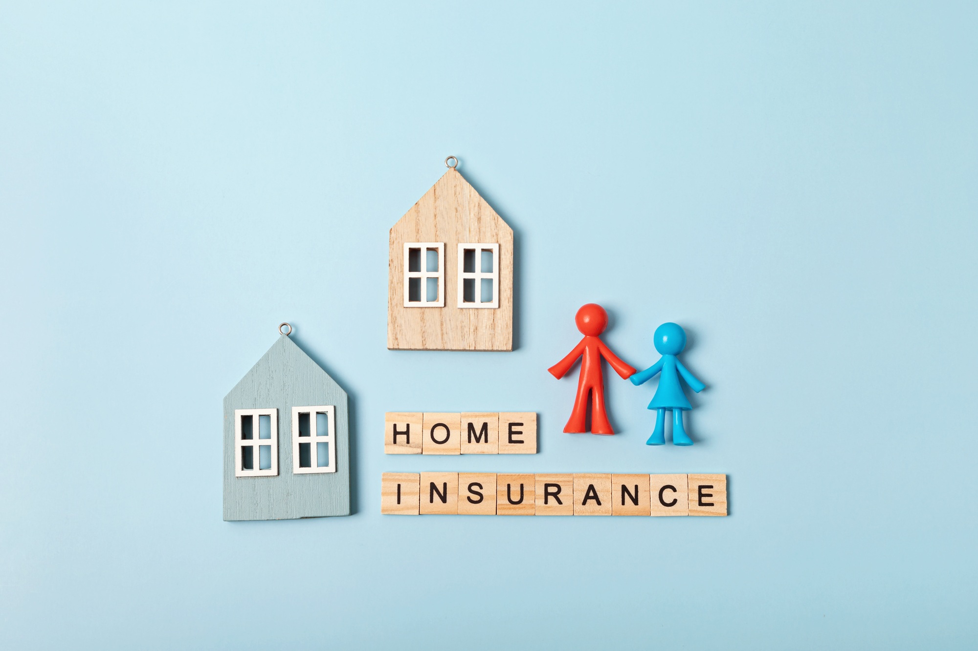 Home insurance message and wooden houses over blue background