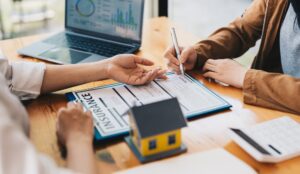 Real estate home are pointing to insurance contract signing and are explaining to customers at the